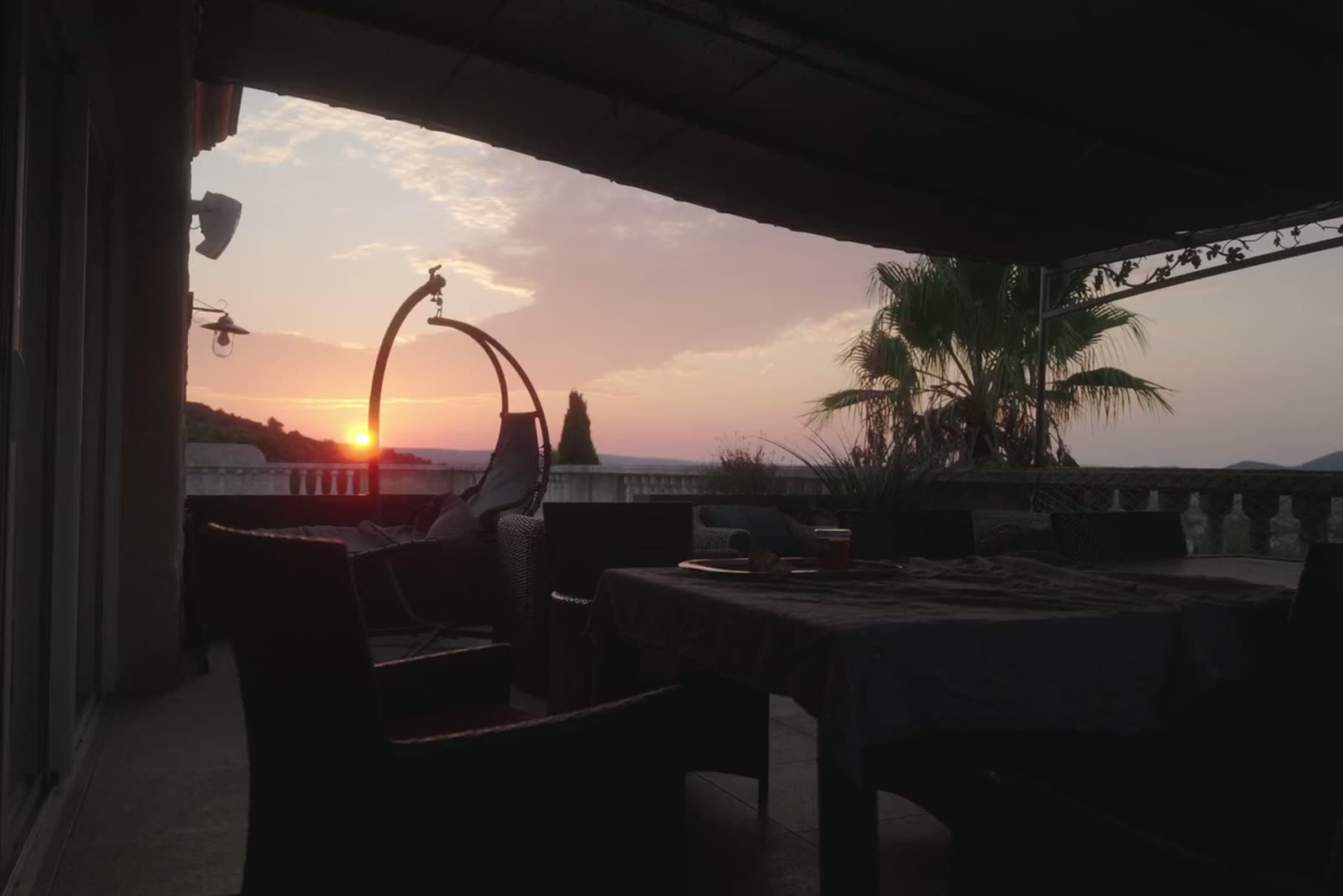 Terrasse couverte à l'heure dorée, le soleil bas dans le cadre.