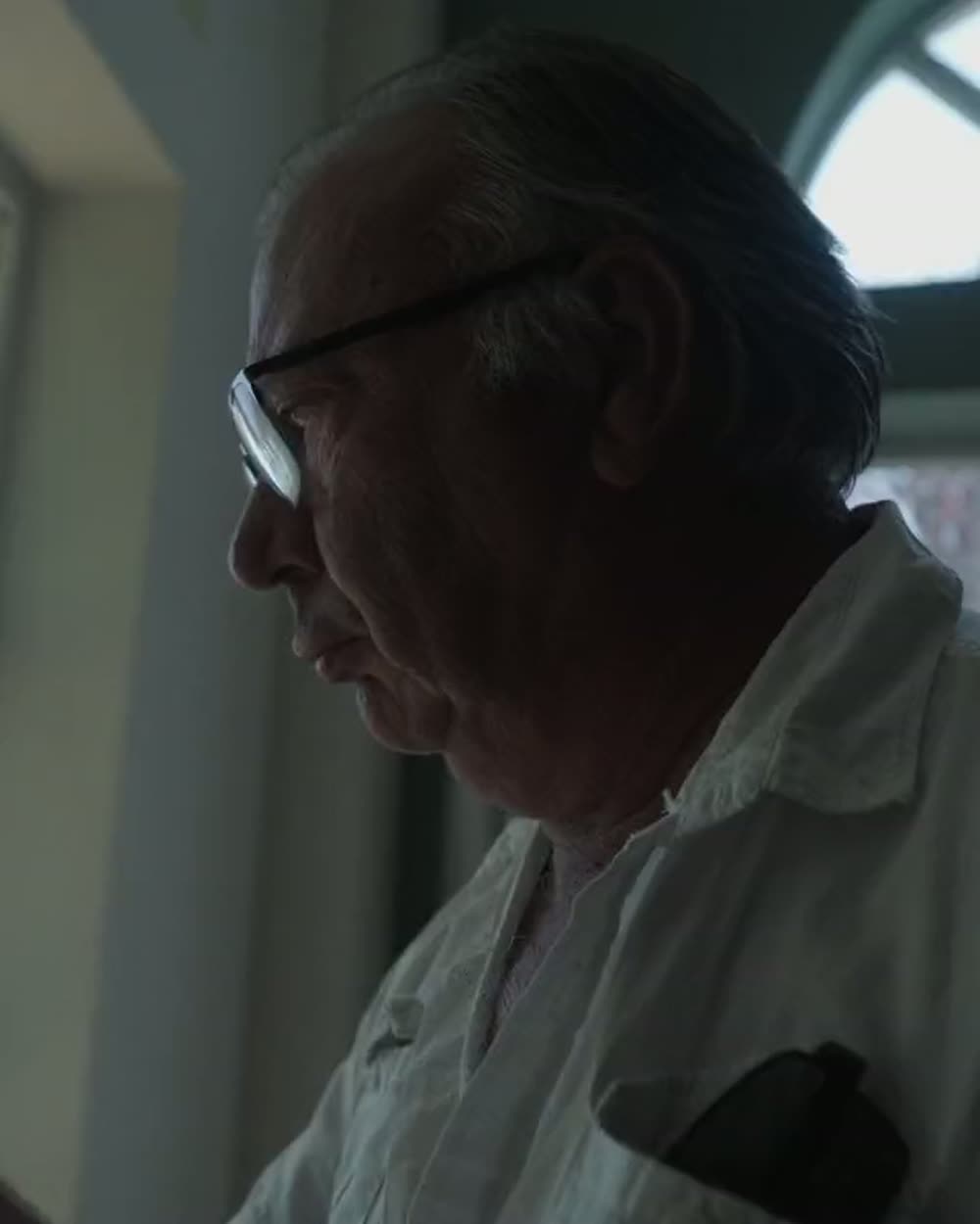 Portrait serré d'un vigneron de profil, lumière rasante venue d'une fenêtre.
