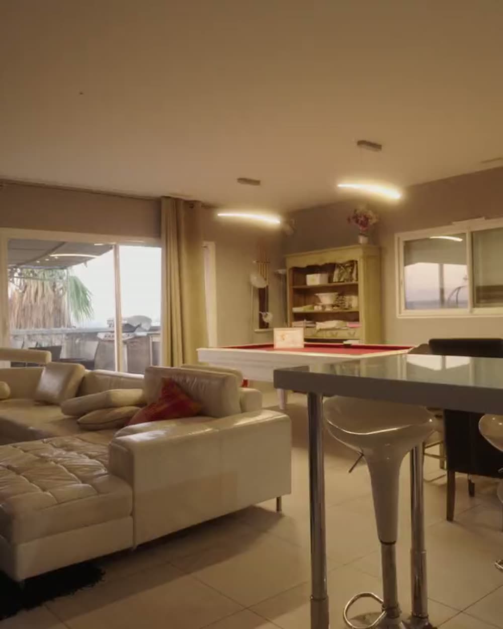 Séjour ouvert sur une baie vitrée, cuisine en second plan, lumière naturelle.